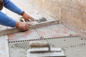 Tile Installation by worker with leveler